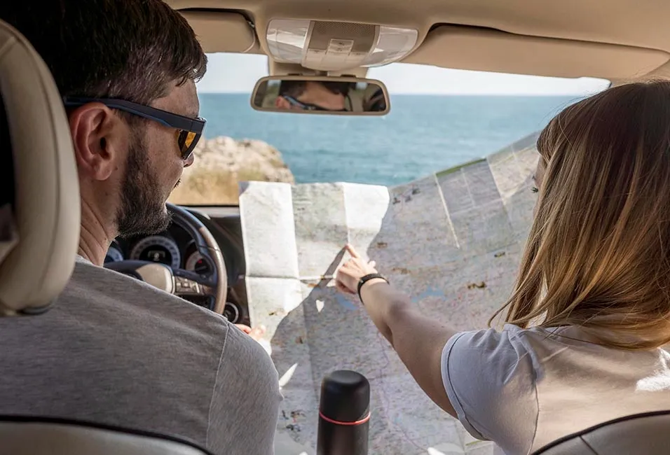 Duas pessoas no carro olhando para um mapa.