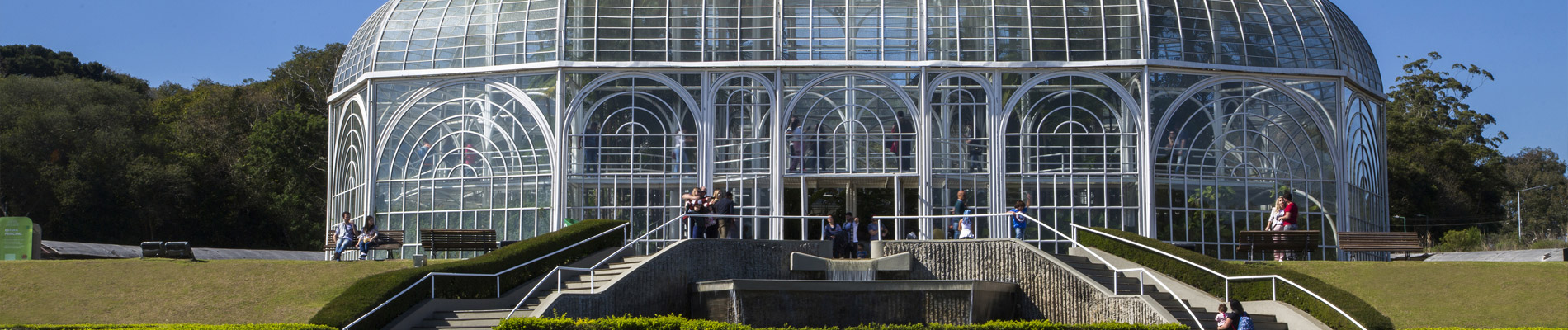 Entrada do Jardim Botânico, estrutura de vidro com escadas e árvores ao fundo
